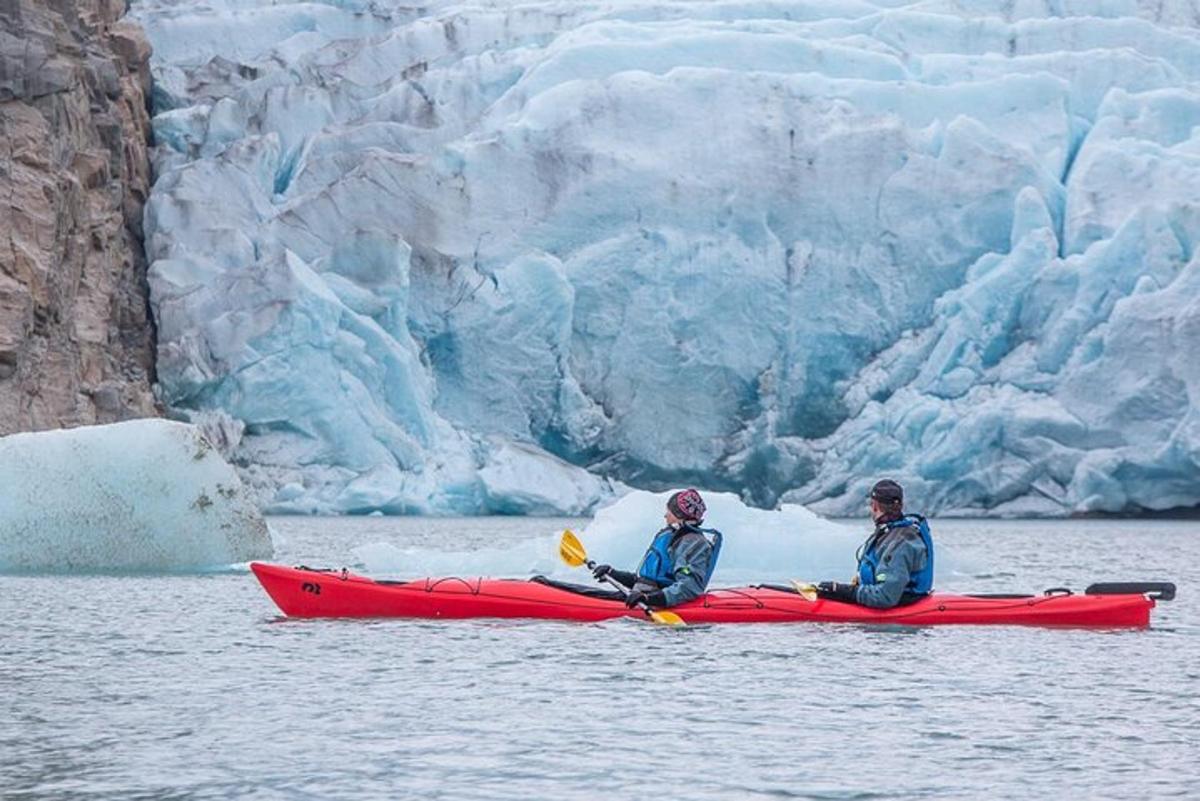 Dos personas en un kayak frente a un glaciar.