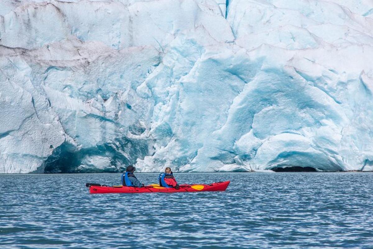 Dos personas en un kayak frente a un glaciar.
