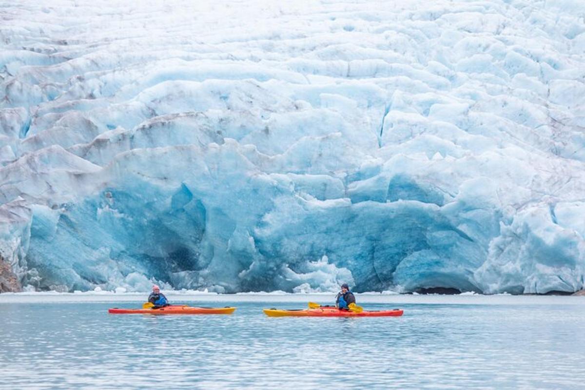 Dos personas en kayaks frente a un glaciar