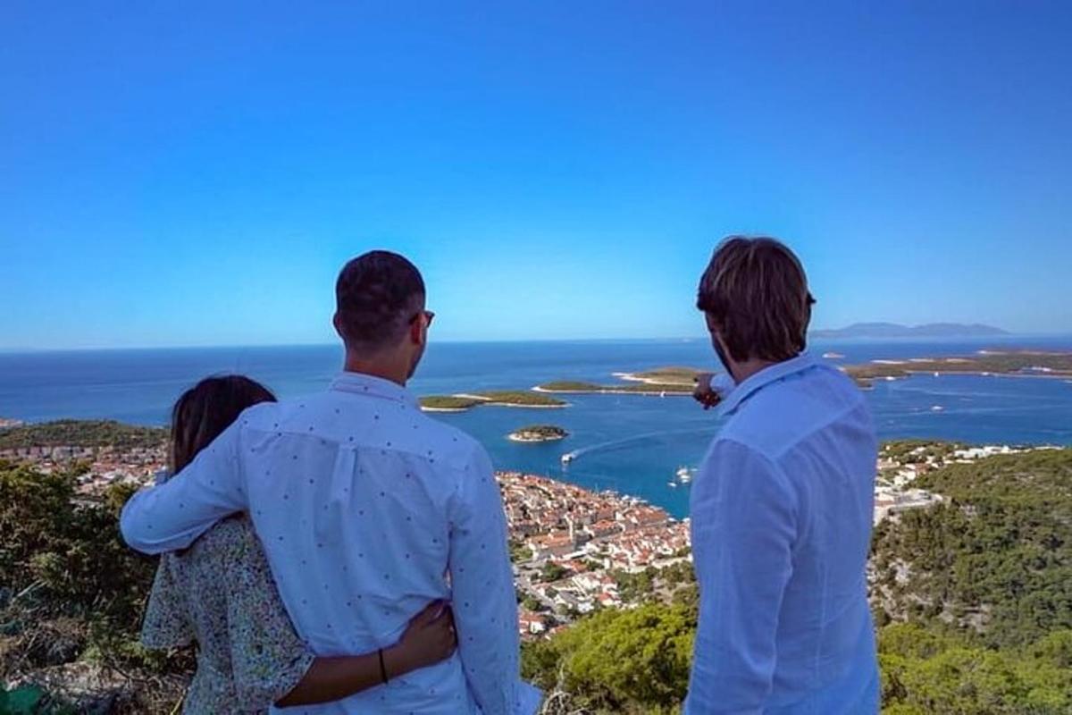 tre persone in piedi in cima a una collina che guardano l'oceano