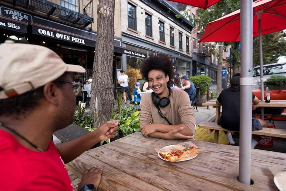 two men sitting at a table with a plate of pizza