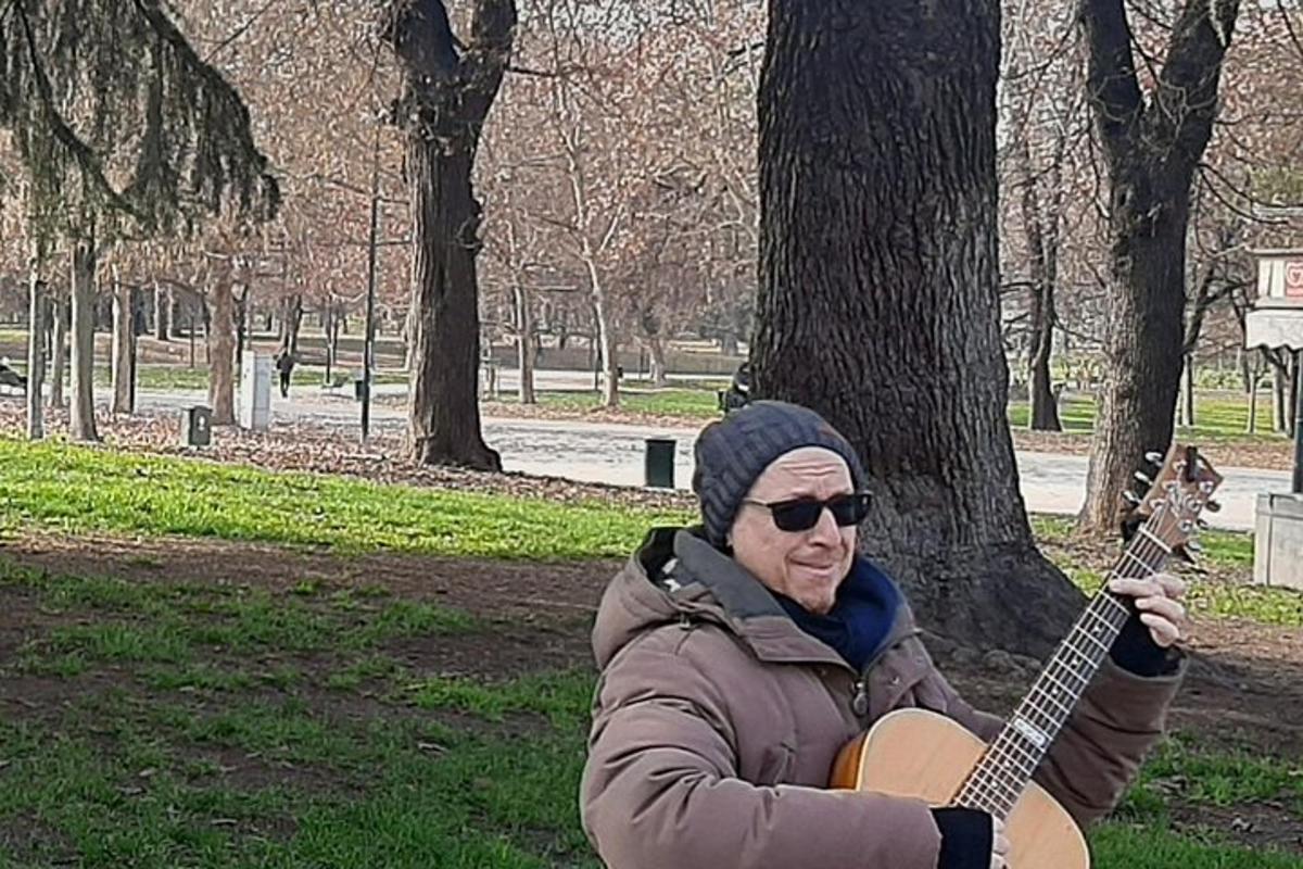 seorang lelaki memegang gitar di sebuah taman