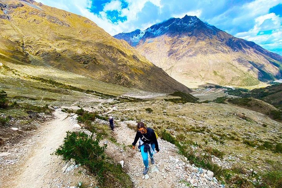 Dos personas caminando por un camino de tierra en una montaña.