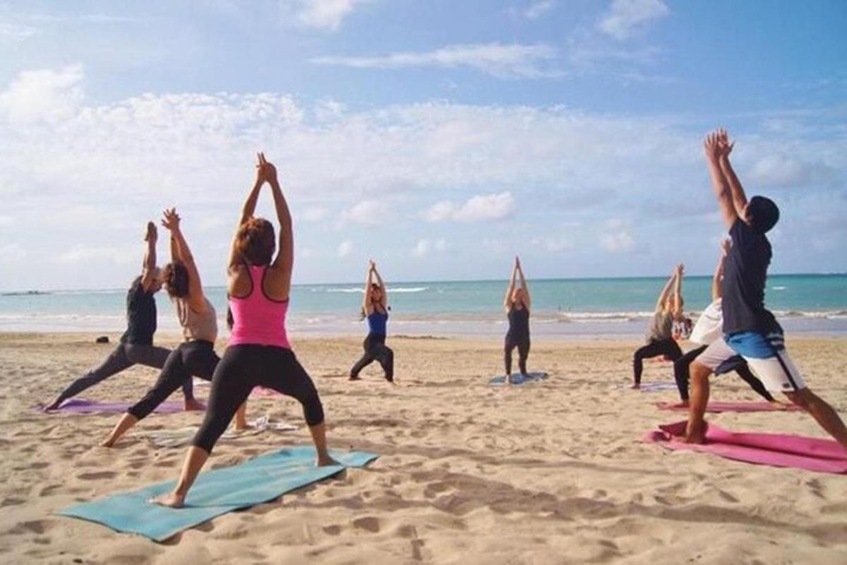 a group of people doing yoga on the beach