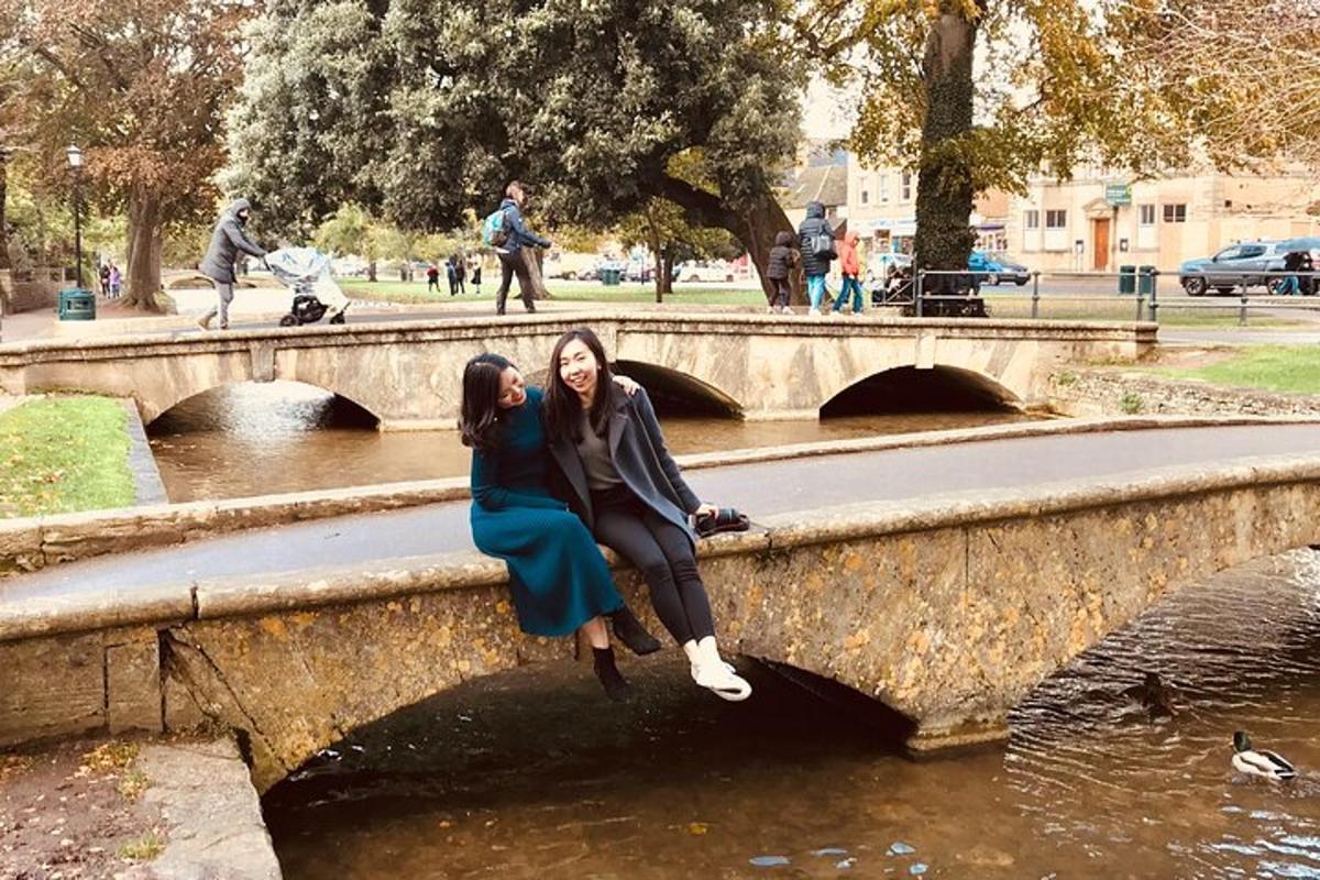 two women sitting on a bridge over a river