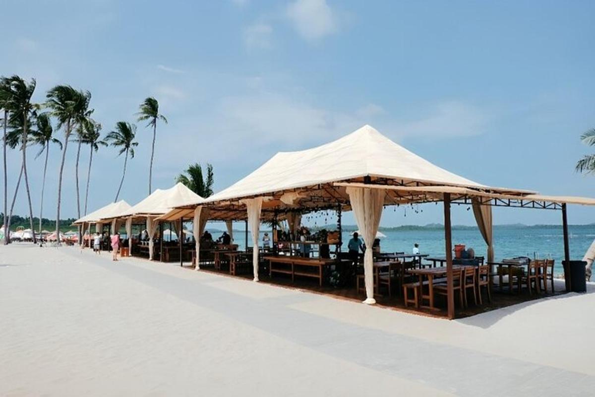 eine Reihe von Tischen und Sonnenschirmen an einem Strand
