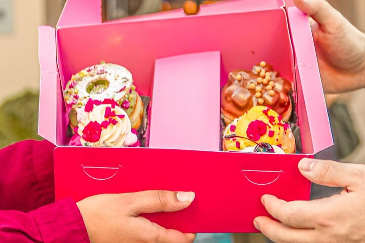 un bambino che tiene in mano una scatola rosa di ciambelle
