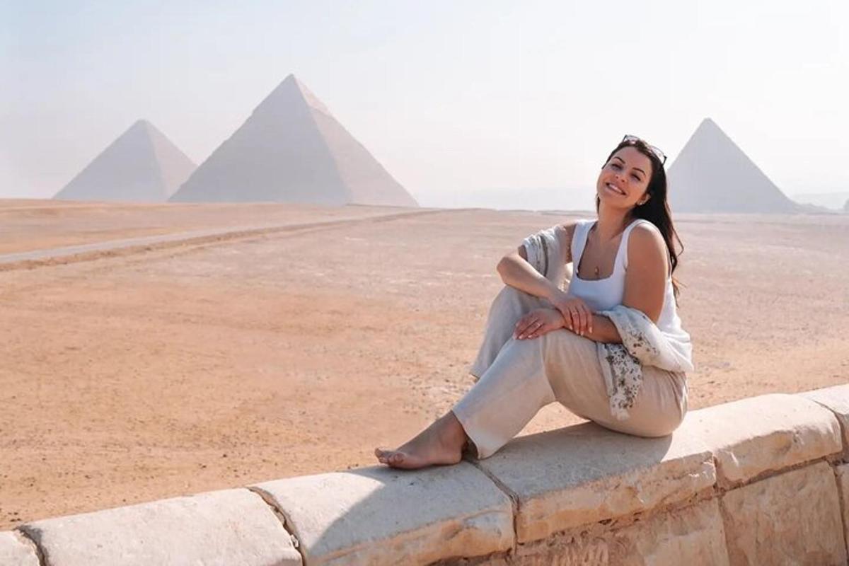 una donna seduta su un muro di fronte alle piramidi
