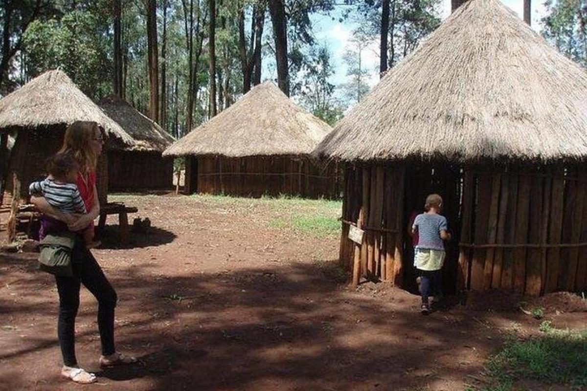 Una mujer y un niño de pie frente a dos chozas