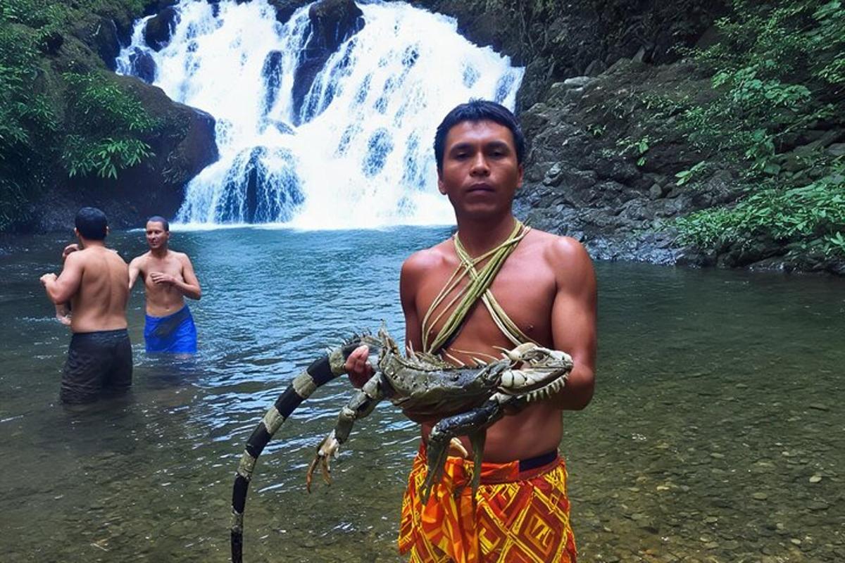 un home que sosté una serp davant d'una cascada