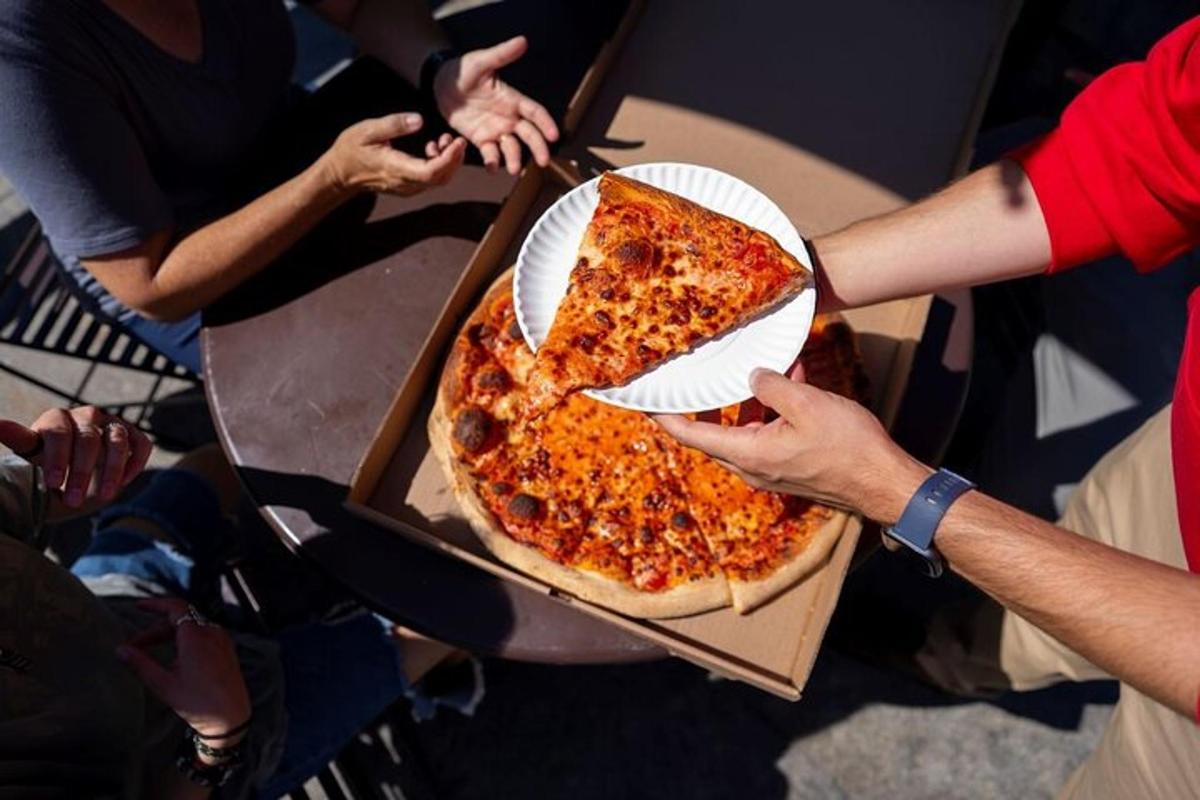 osoba držící velkou pizzu v krabici