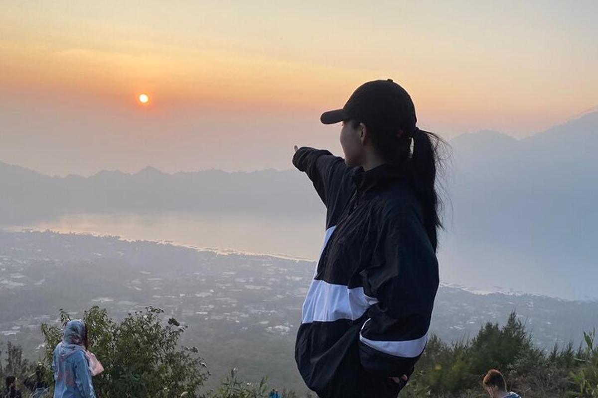 žena stojaca na kopci a pozerajúca sa na západ slnka