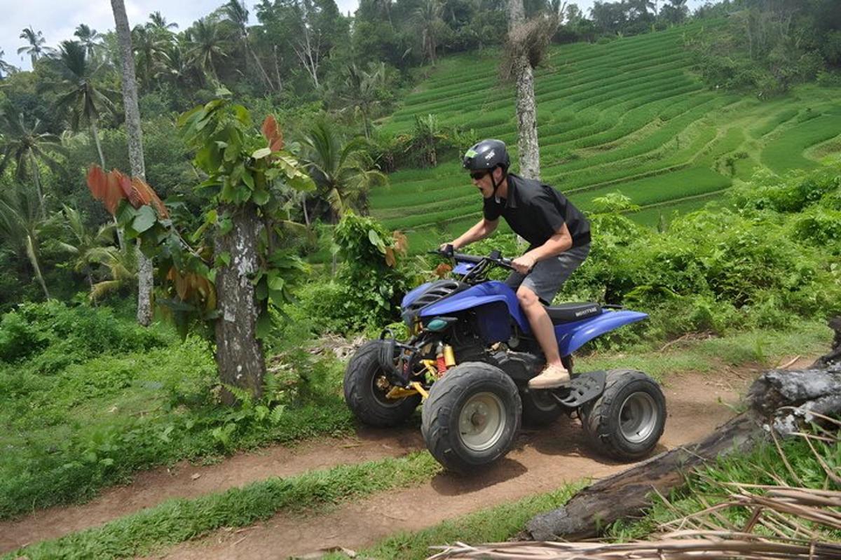seorang lelaki menunggang basikal quad menyusuri jalan tanah