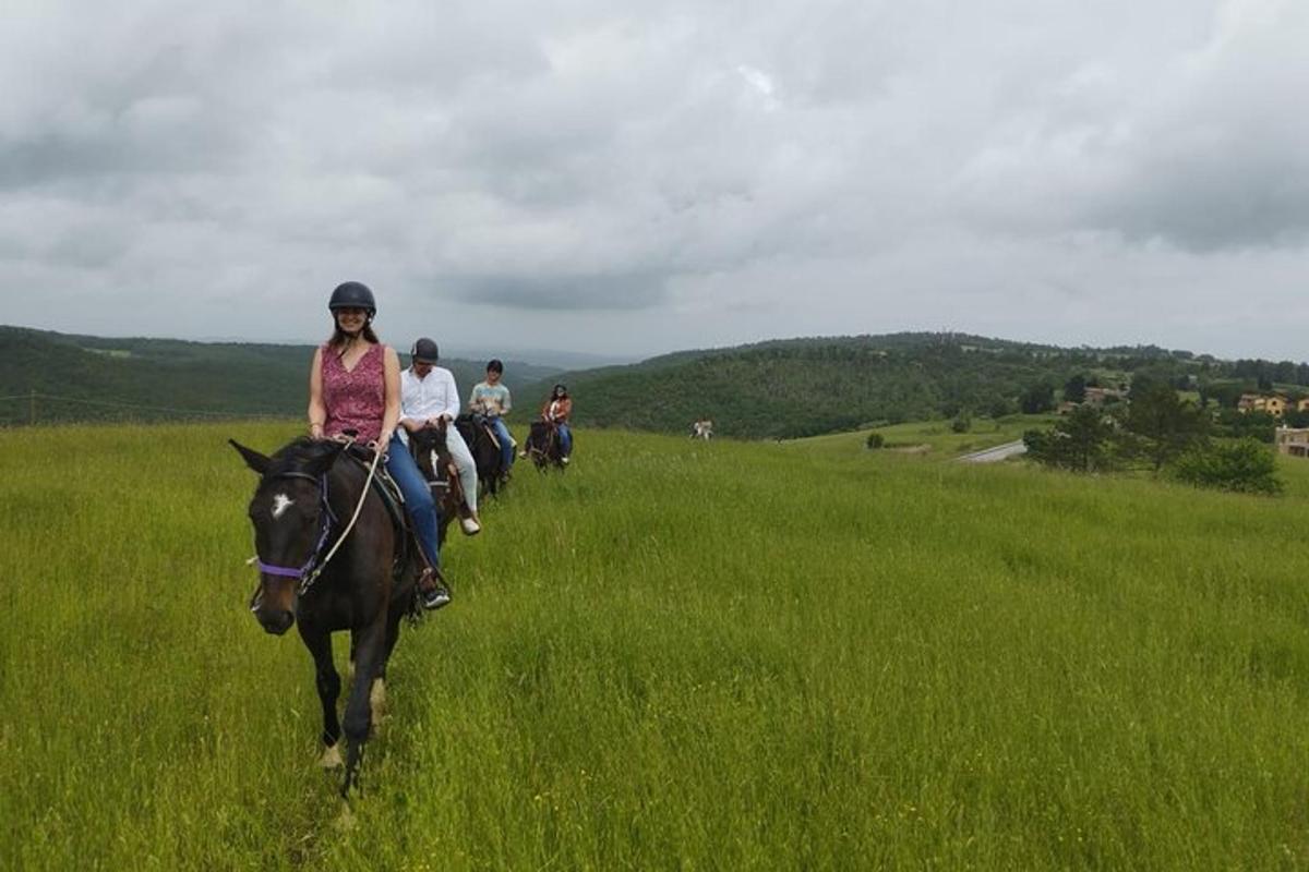 un grup de persones muntant a cavall en un camp