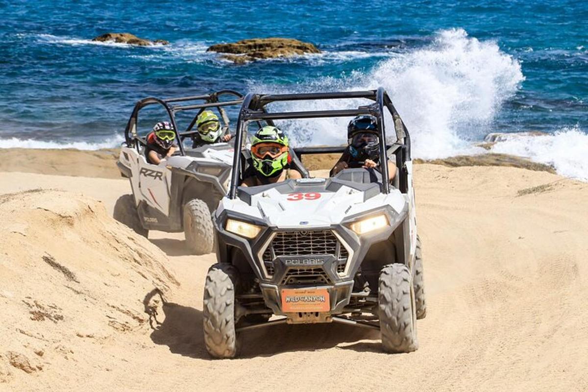 három ember ATV-zik a tengerparton