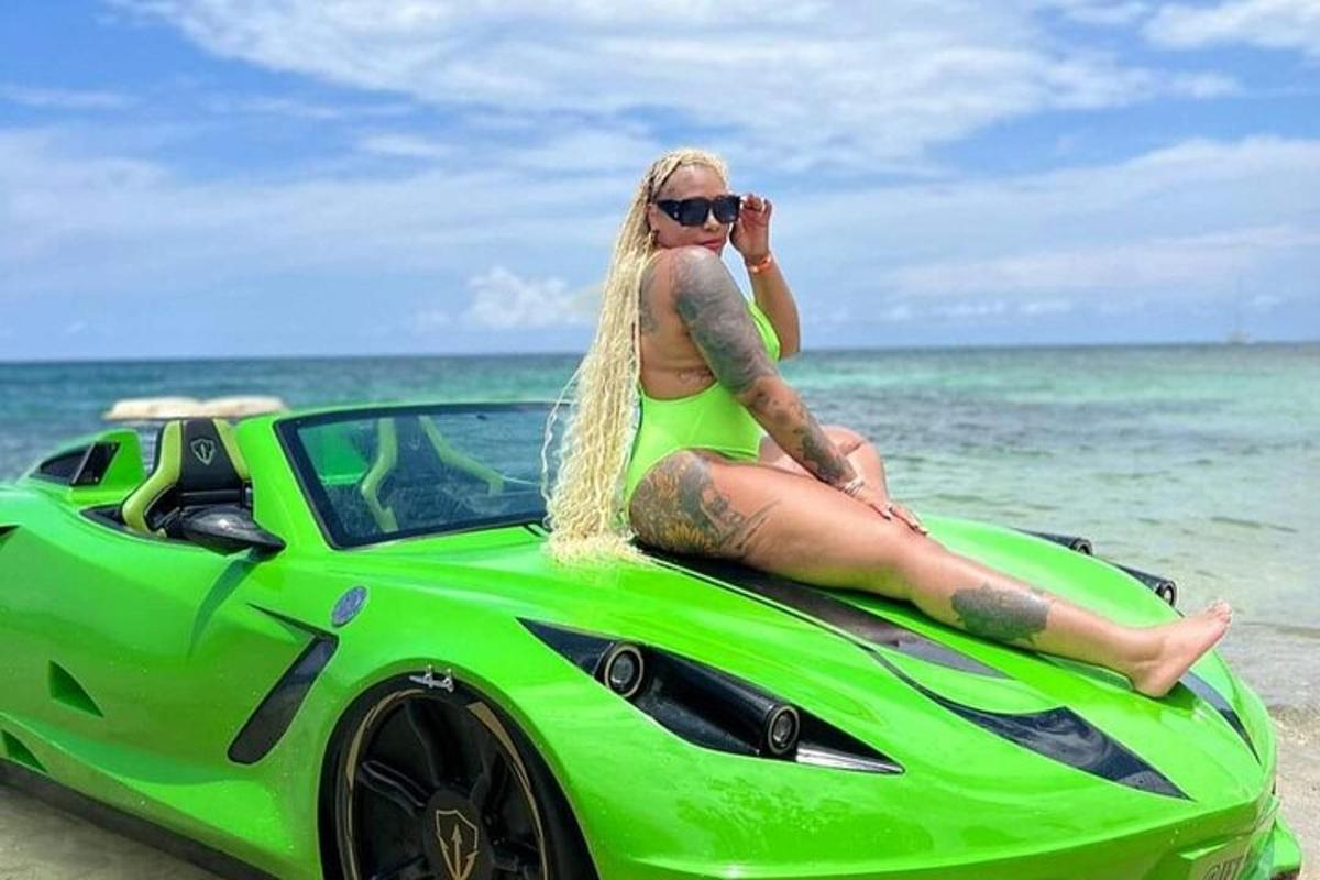 žena sedící na střeše zeleného auta na pláži