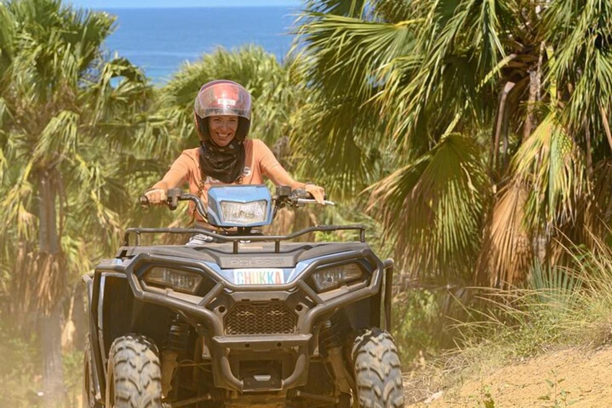 uma mulher pilotando um quadriciclo em uma estrada de terra