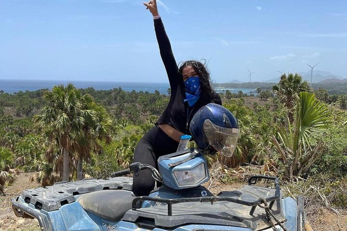 uma mulher em pé em uma motocicleta com a mão no ar