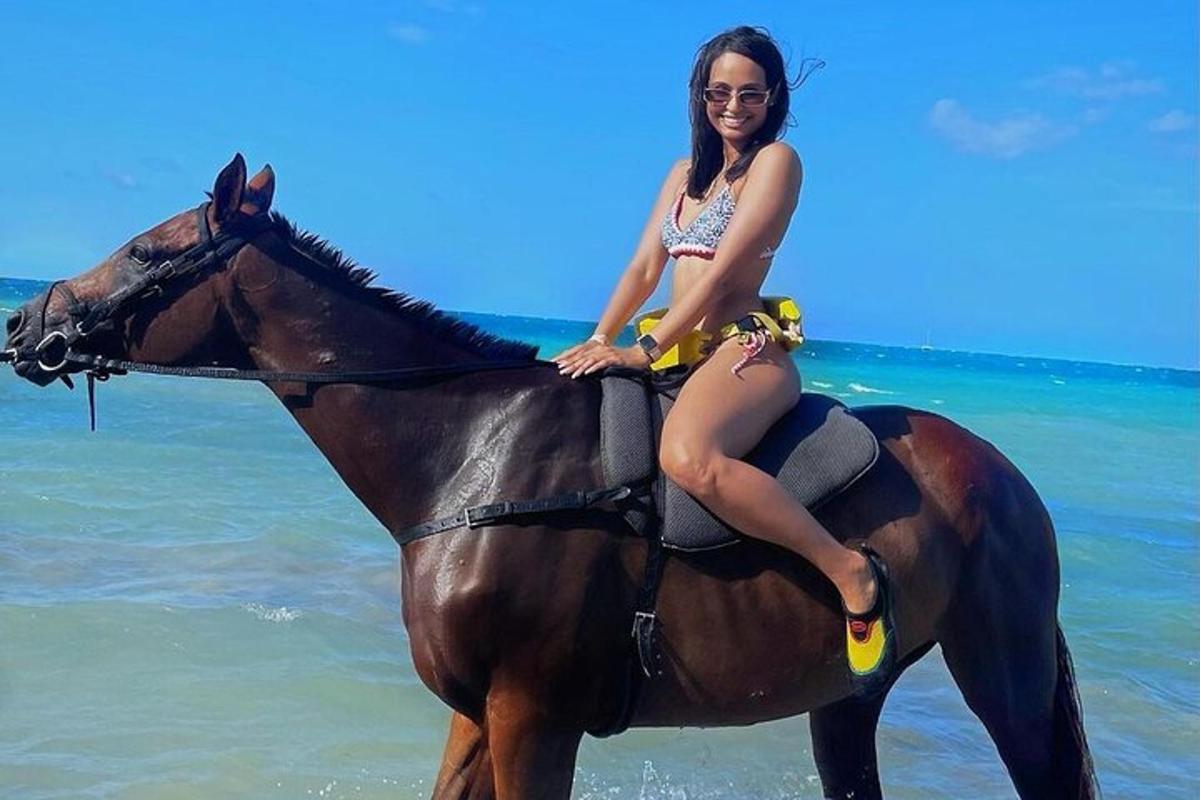 seorang wanita sedang duduk di atas kuda di pantai