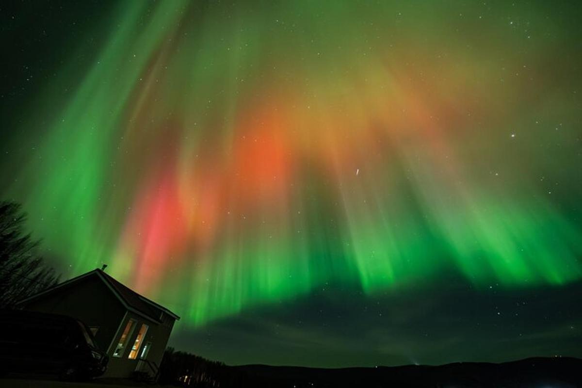 un'aurora nel cielo sopra una cabina con un edificio