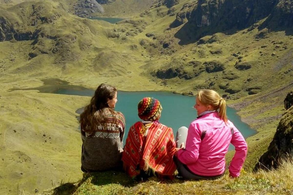 due donne sedute in cima a una montagna che guardano un lago