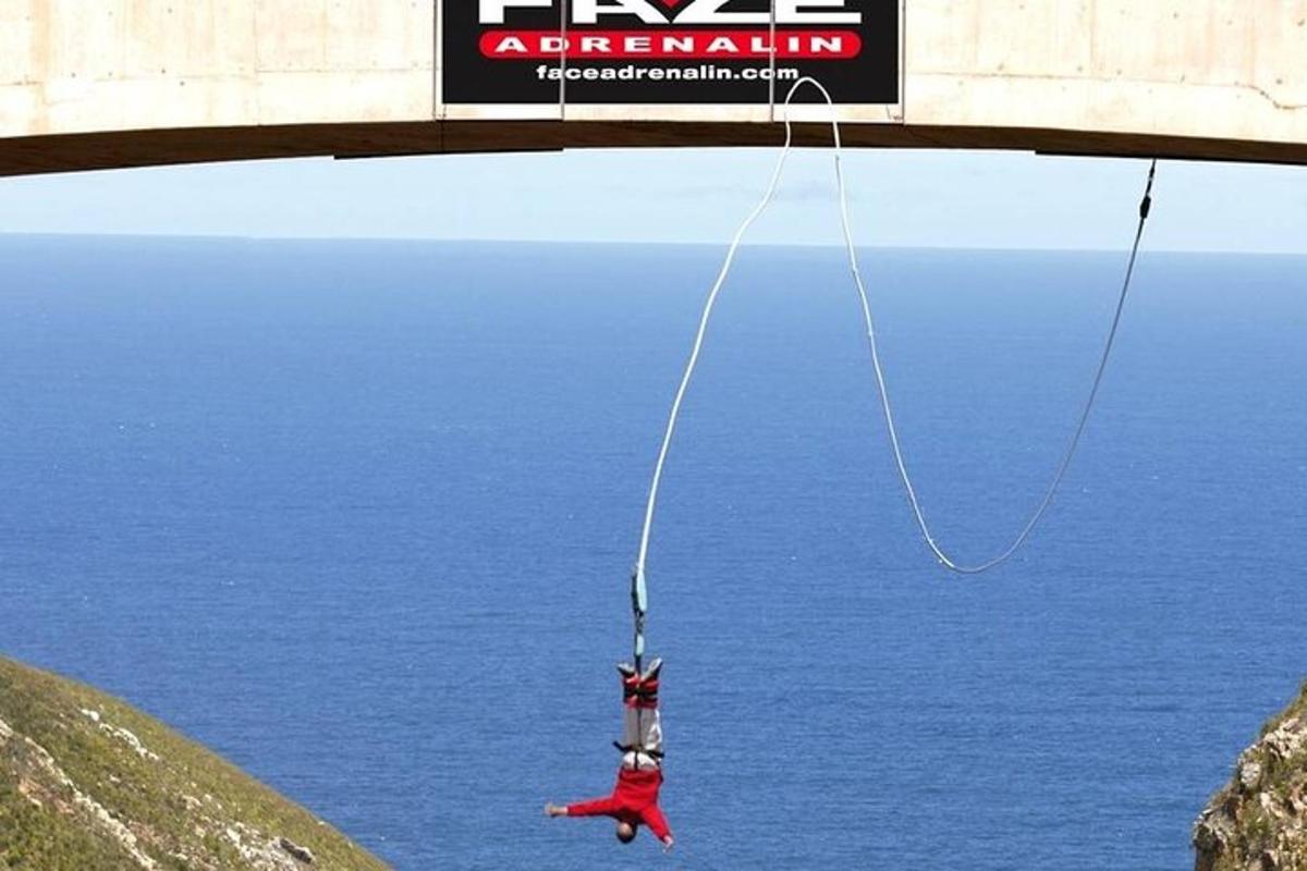 una persona amb una corda penjada d'un pont sobre l'aigua