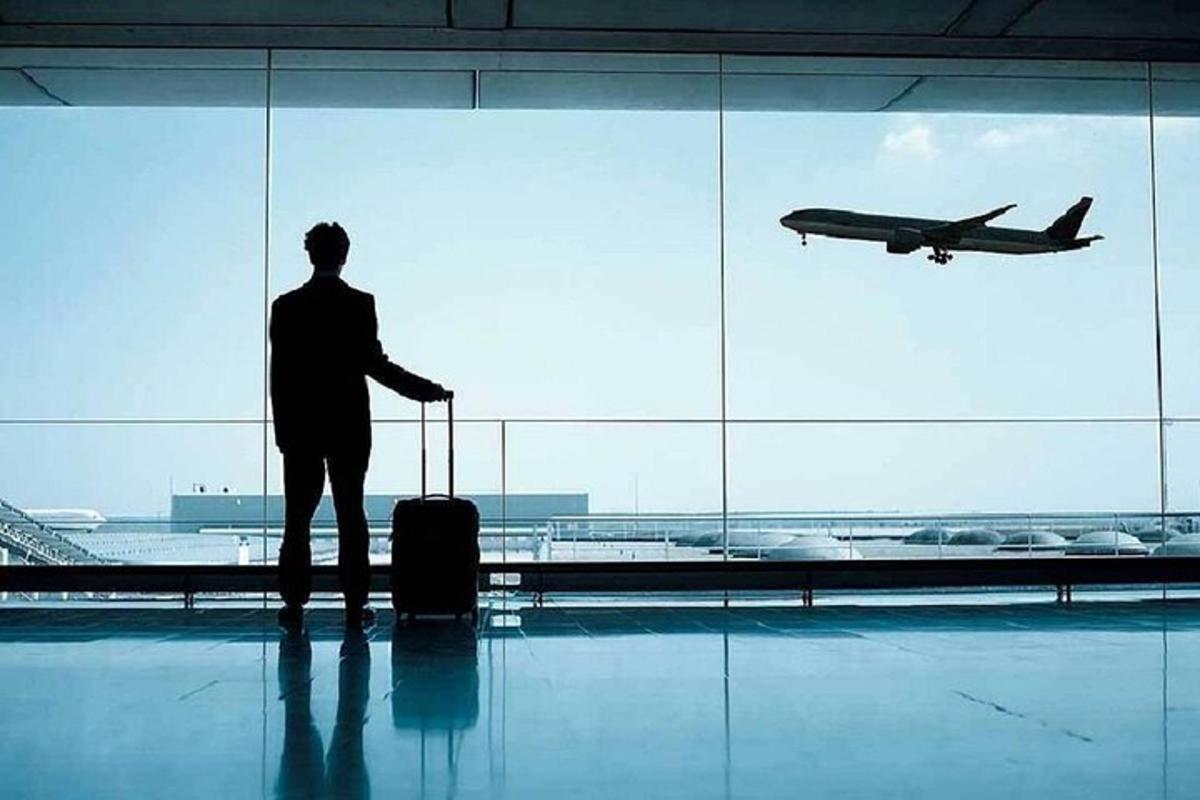 um homem parado em um aeroporto olhando para um avião