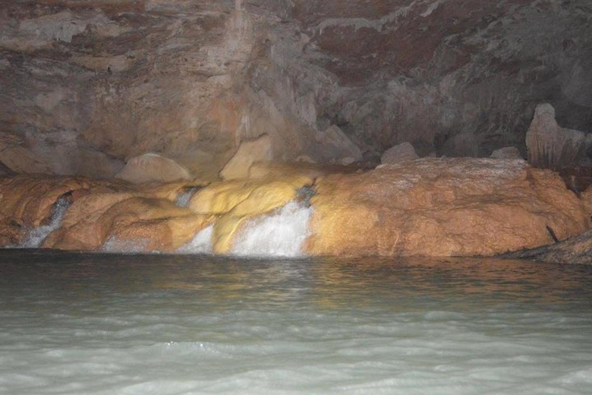 a pool of water in a cave with a waterfall
