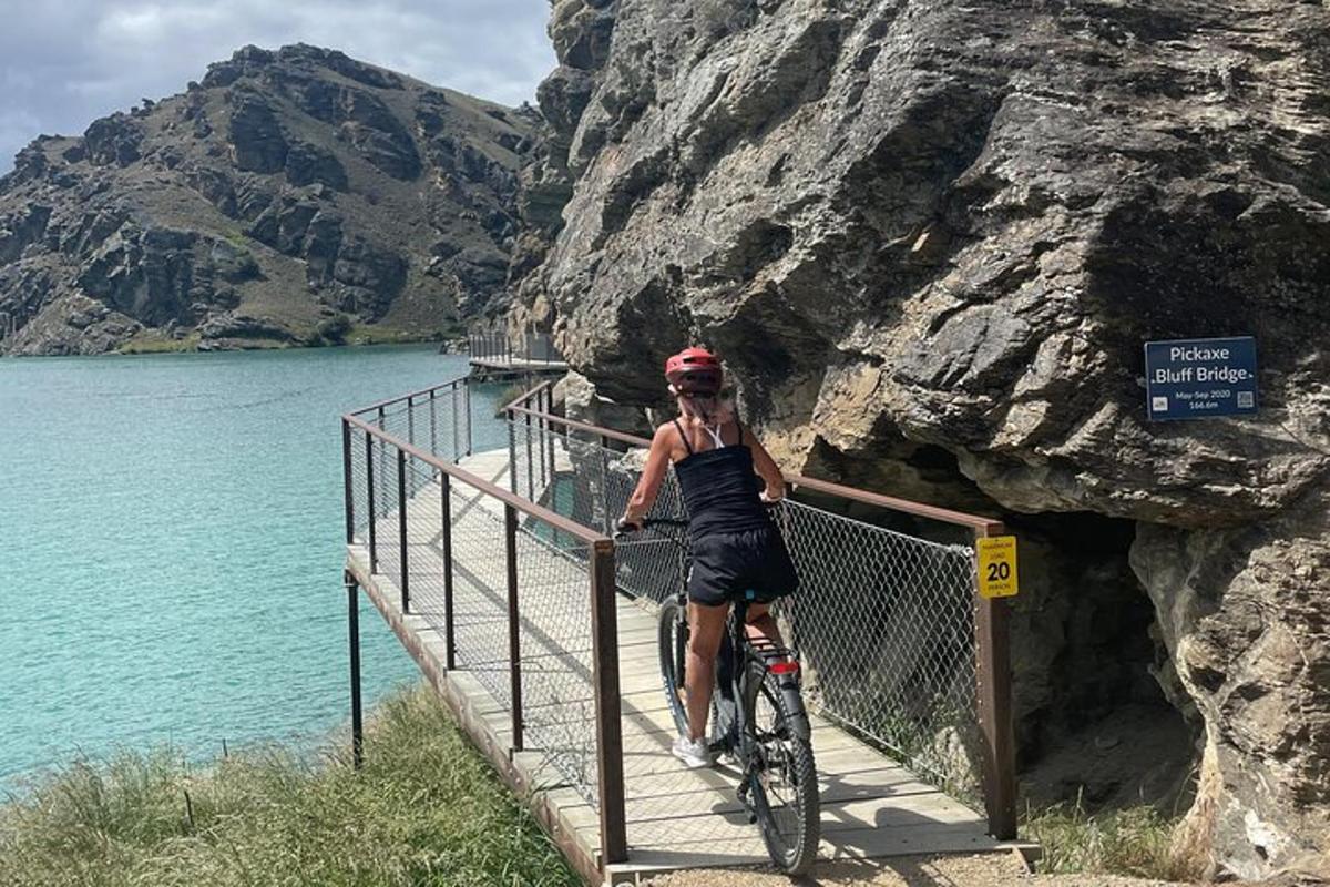 Una mujer montando en bicicleta en un puente sobre un lago