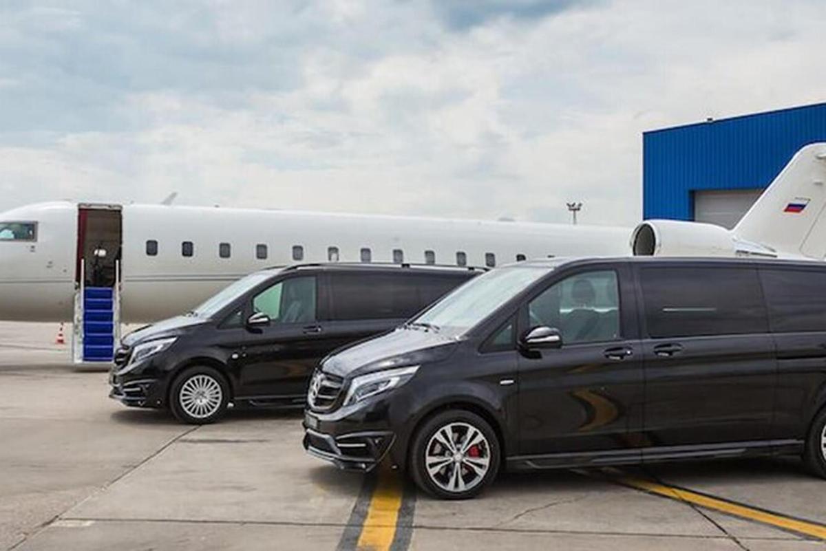 two black vans parked next to an airplane