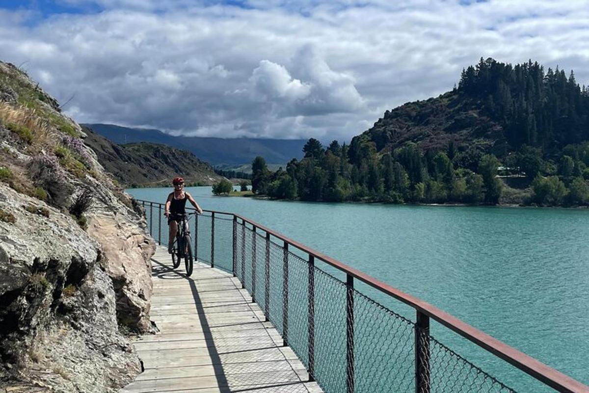 osoba jedoucí na kole po mostě přes jezero