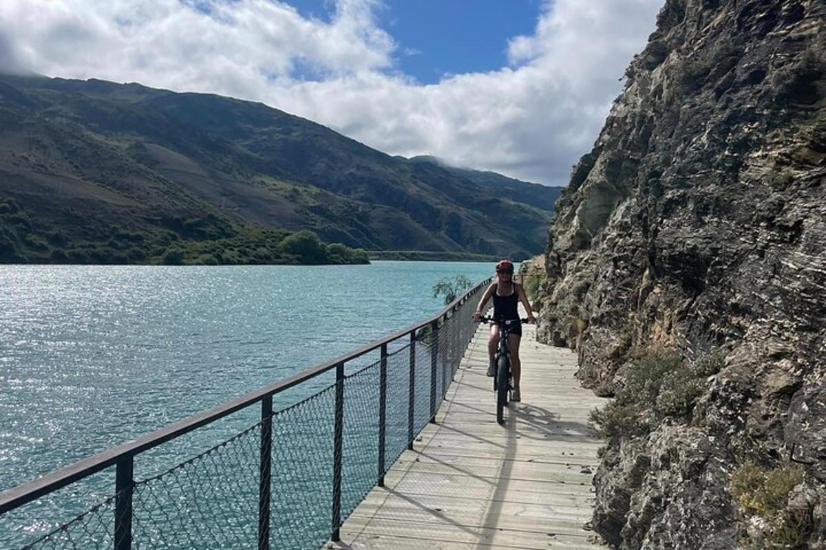 una persona anant en bicicleta per un pont sobre un llac