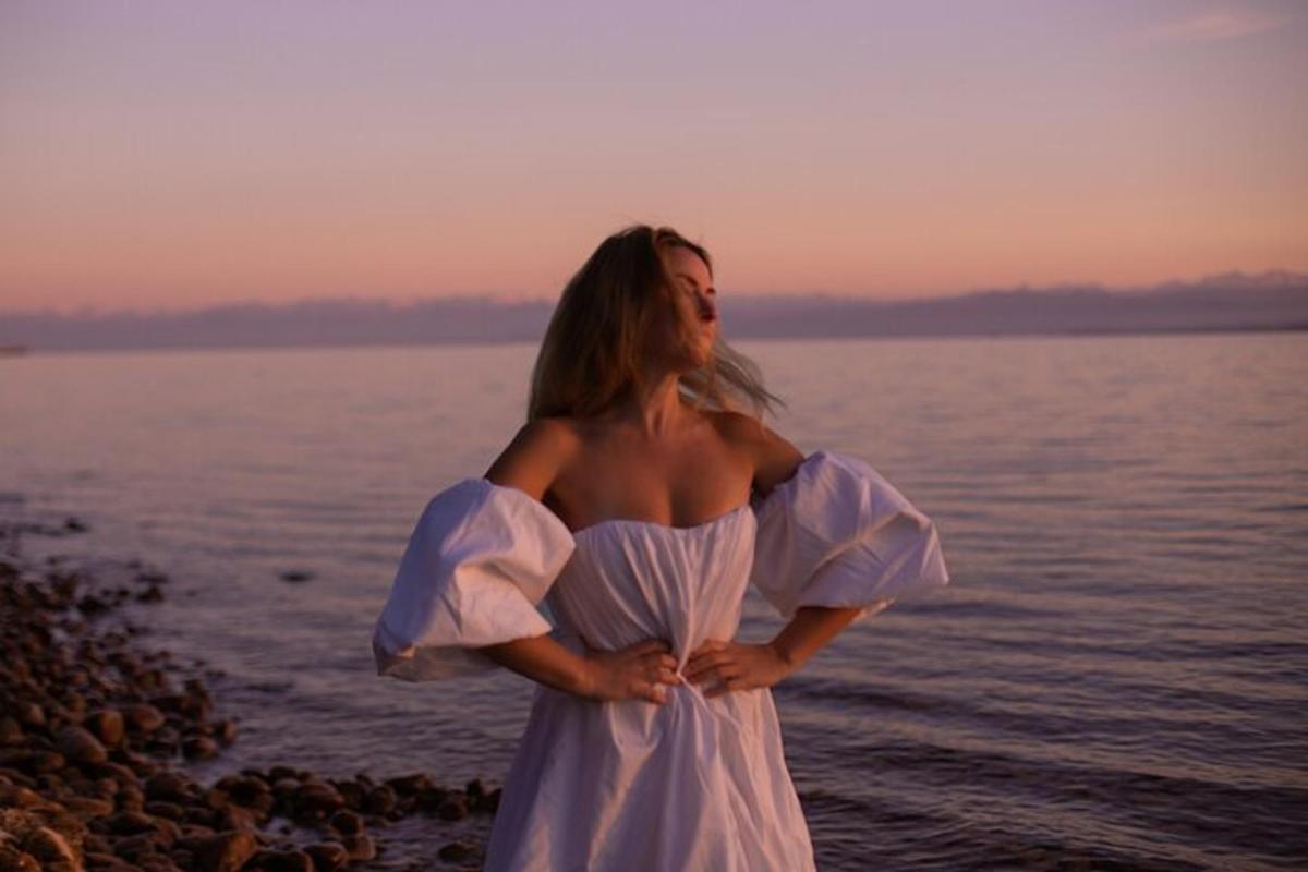 ženska v beli obleki, ki stoji na plaži