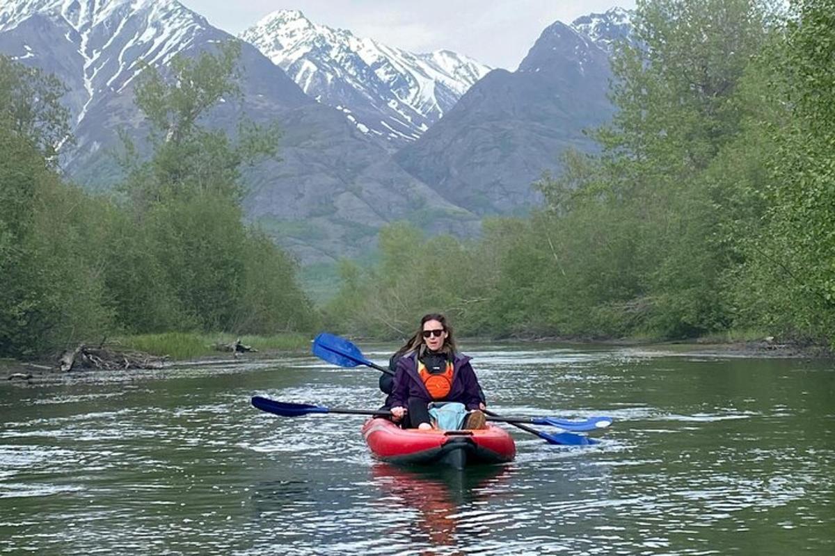 una donna in kayak su un fiume con montagne