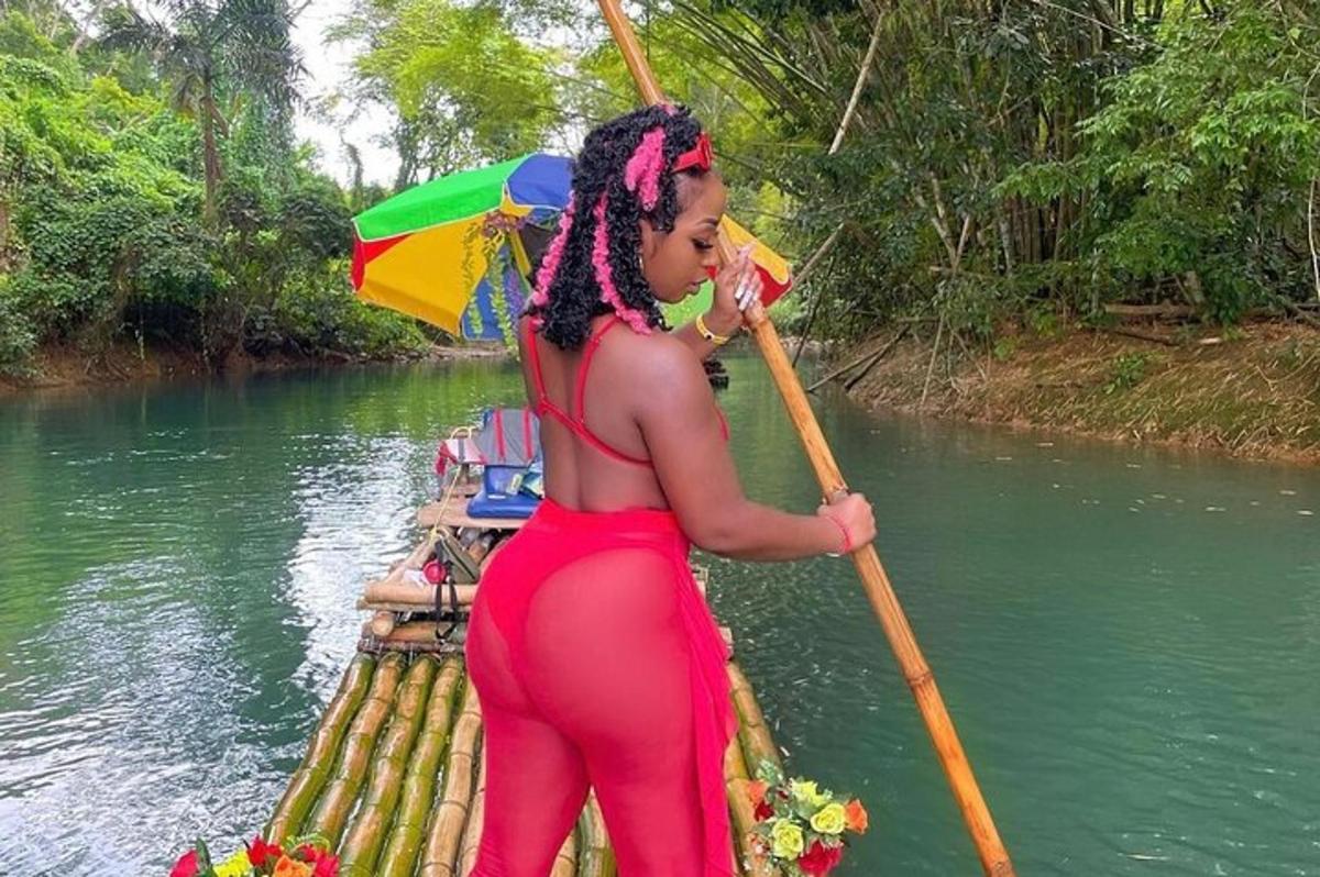una donna con un vestito rosso che rema su una barca su un fiume