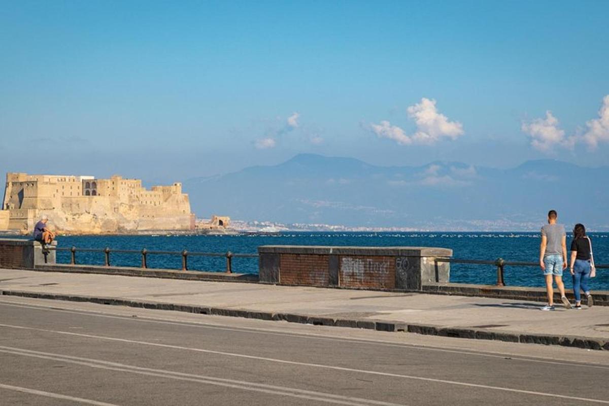 doi oameni mergând pe un trotuar lângă ocean