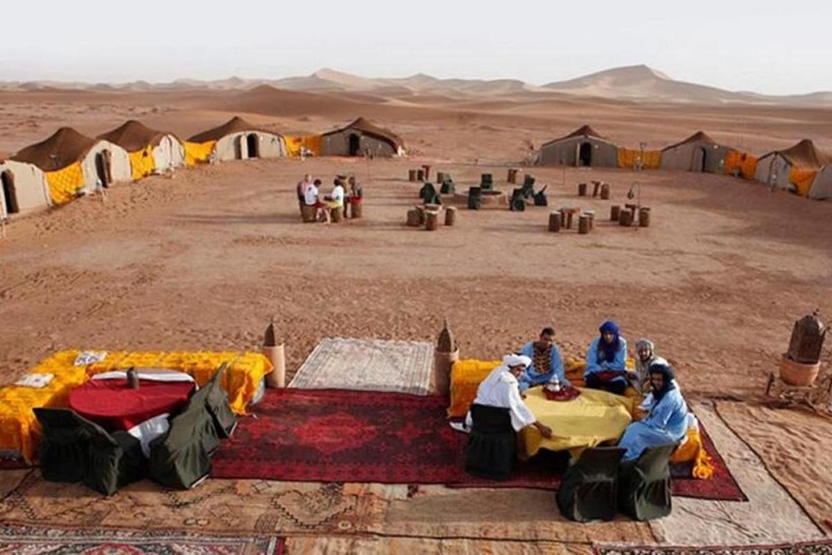 un gruppo di persone sedute davanti alle tende nel deserto