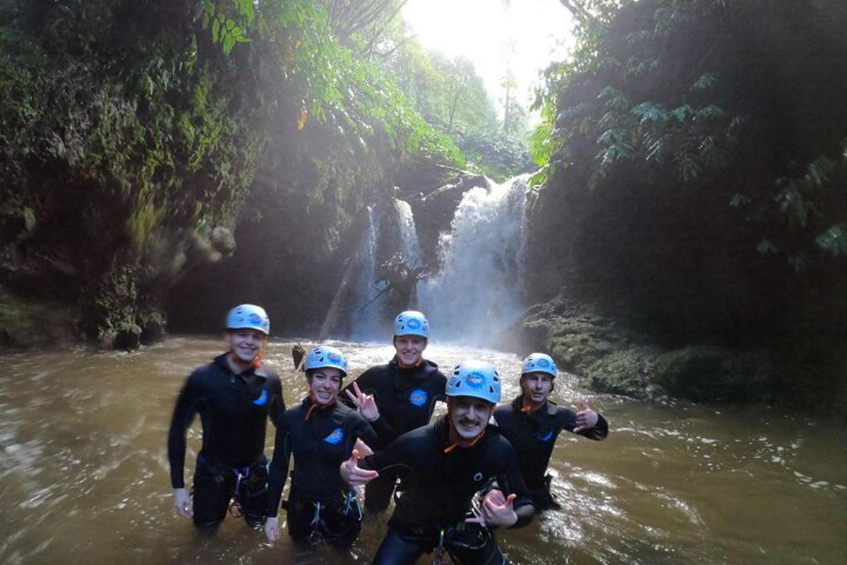 sekumpulan orang di dalam air di hadapan air terjun