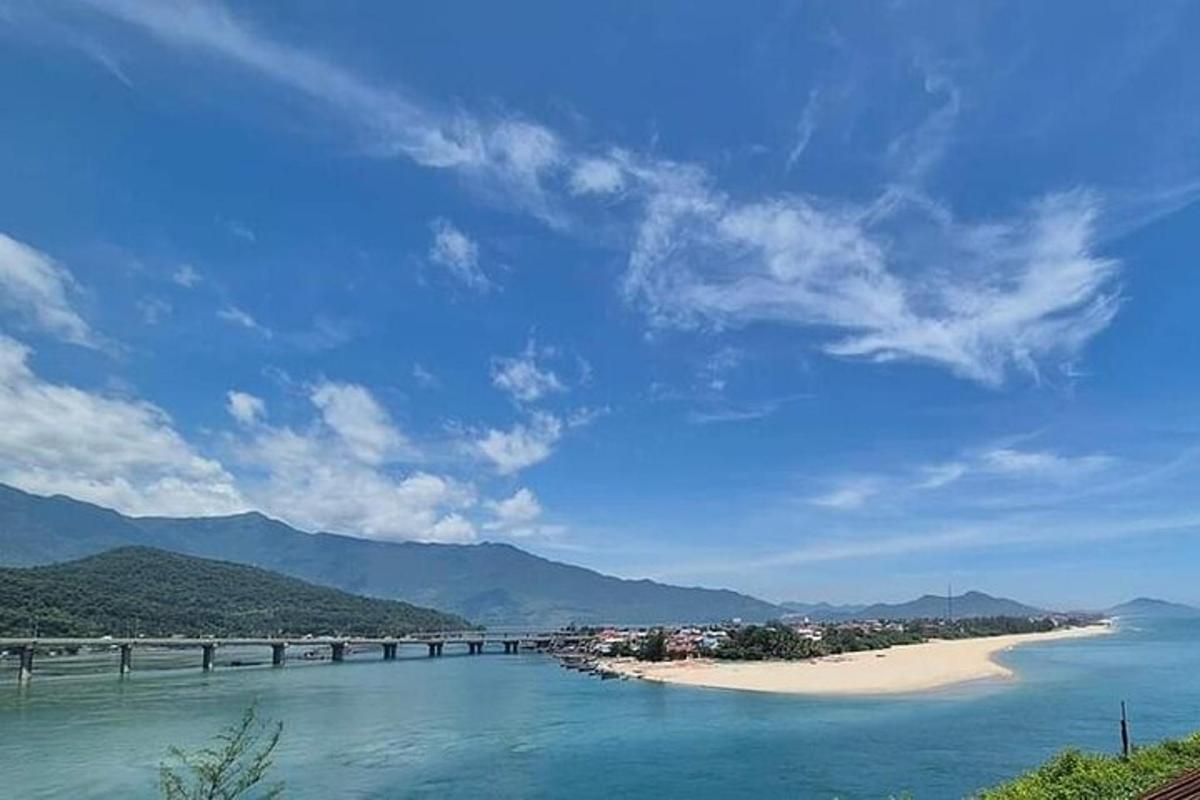 một cây cầu bắc qua sông có bãi biển và núi