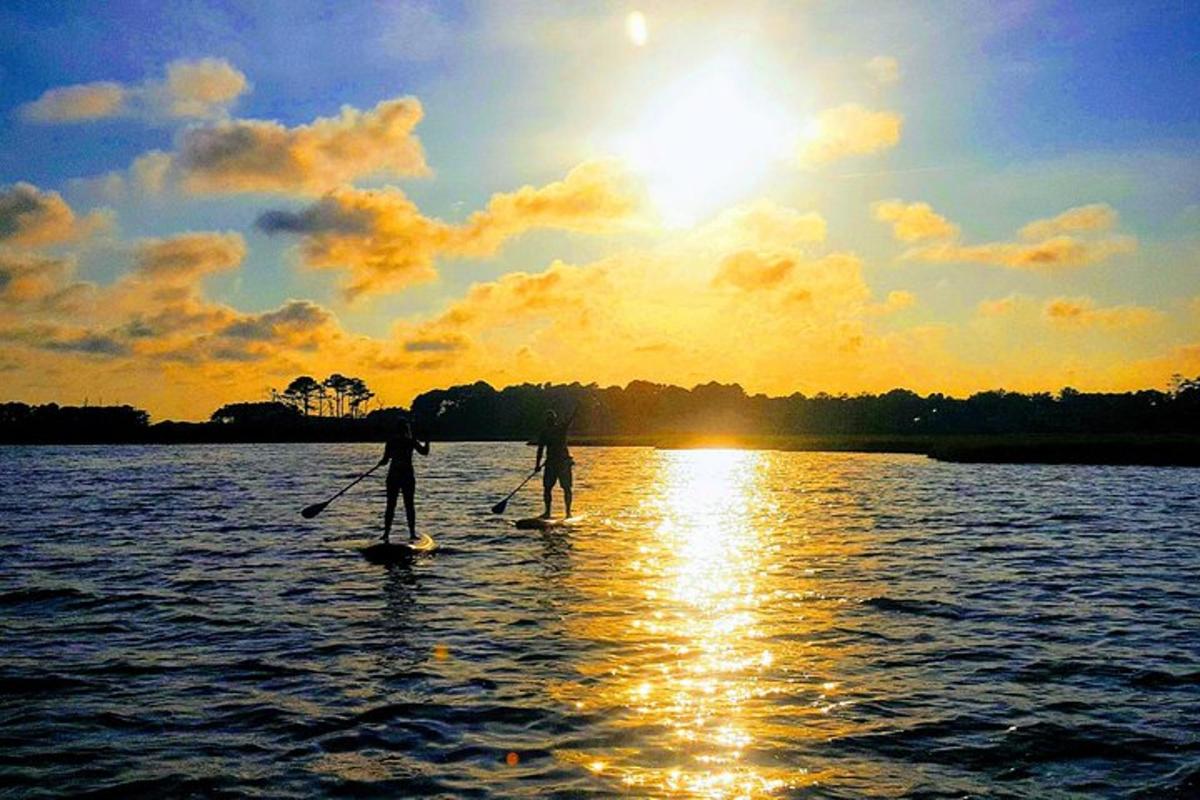 two people are paddle boarding on the water at sunset