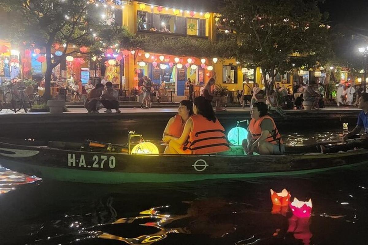 three people sitting in a boat on the water at night