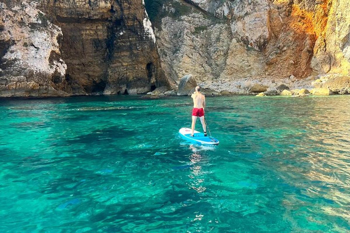 moški, ki stoji na deski za veslanje v vodi