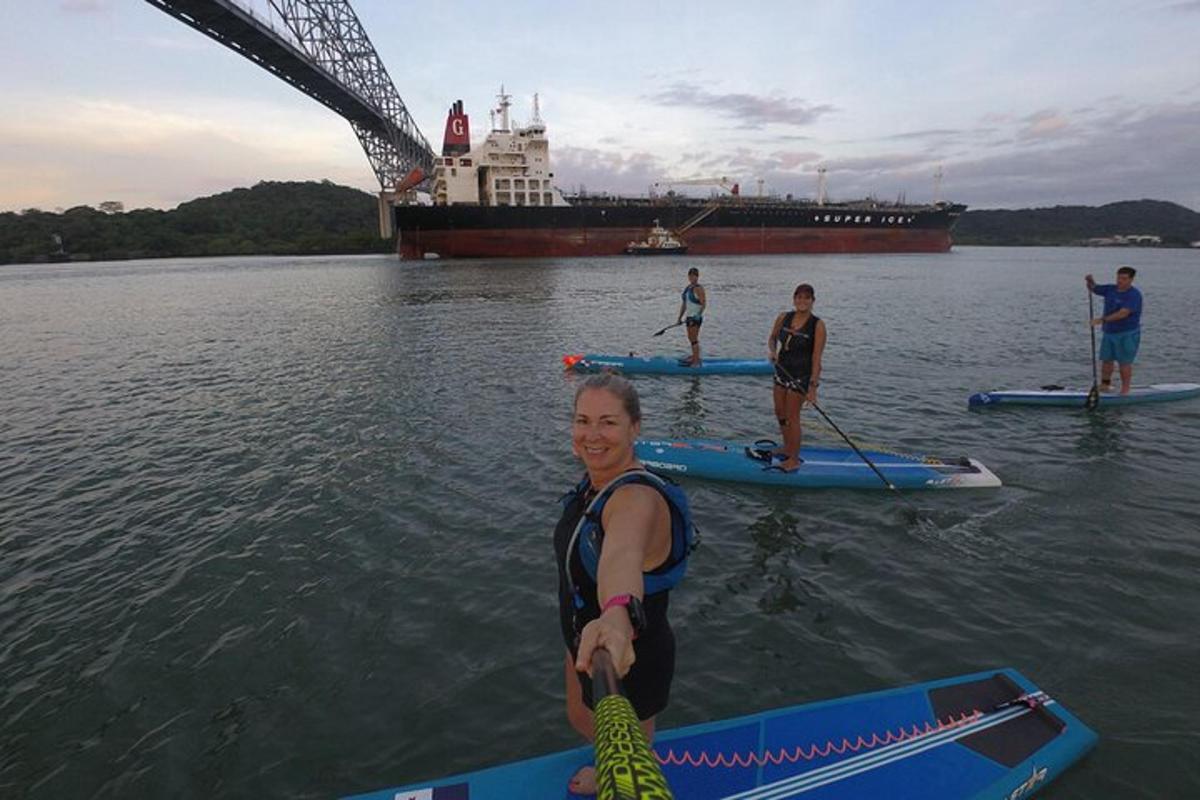 skupina lidí na paddleboardech ve vodě s lodí