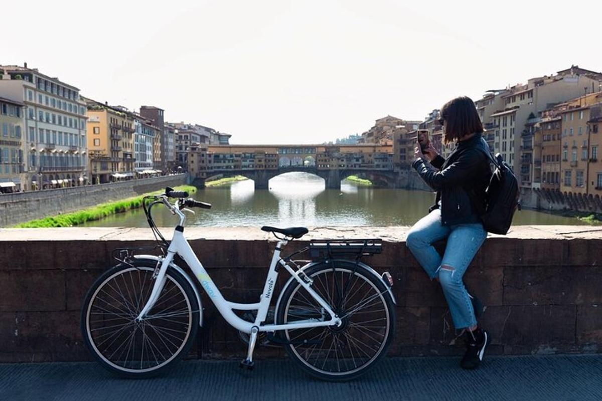 Una mujer sentada en un muro junto a una bicicleta.
