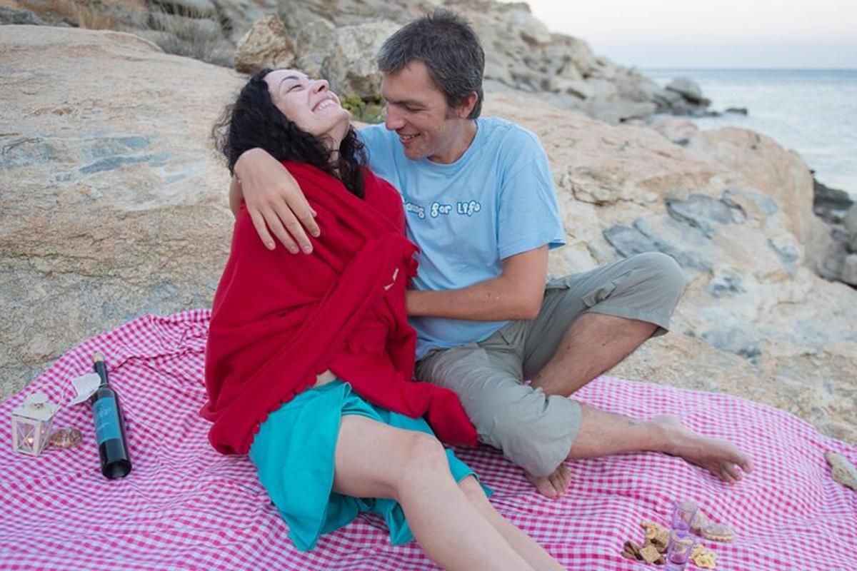 un uomo e una donna seduti su una coperta sulla spiaggia
