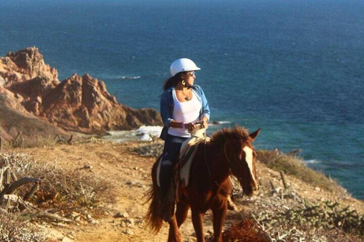 una dona muntant a cavall a la platja