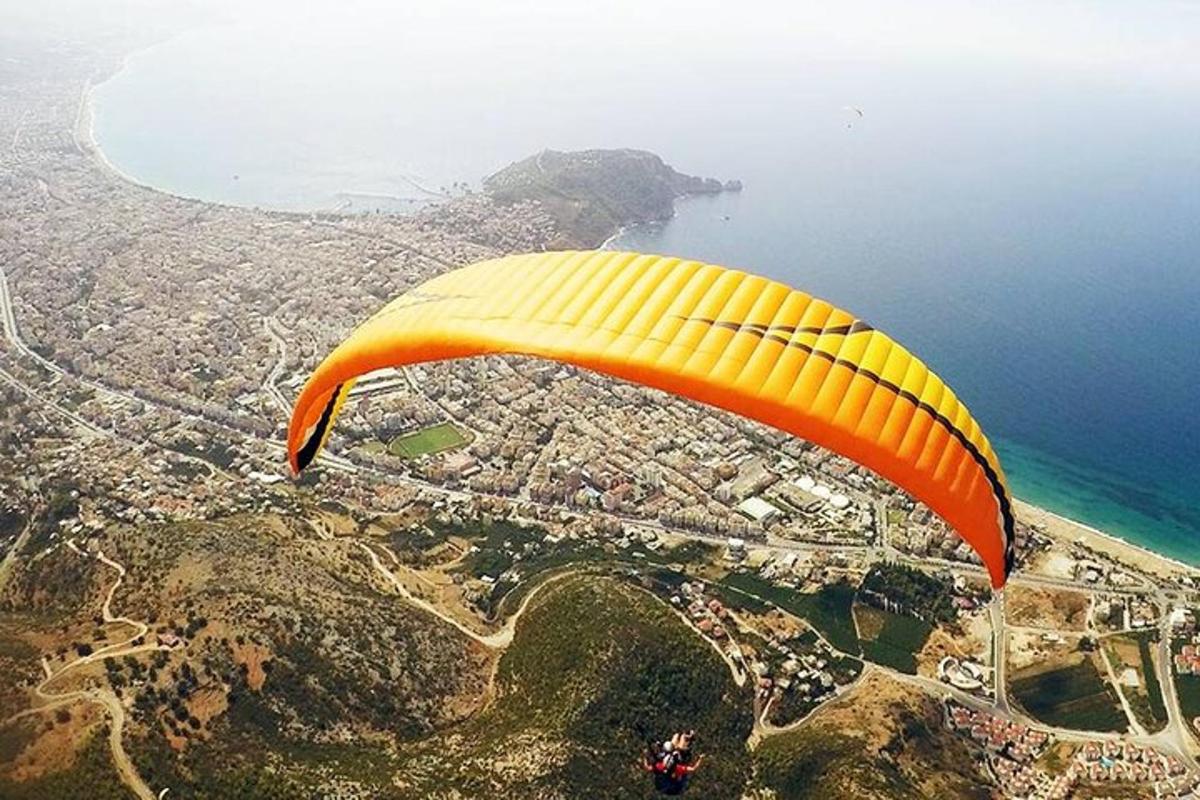 um paraquedas amarelo e laranja voando sobre o oceano