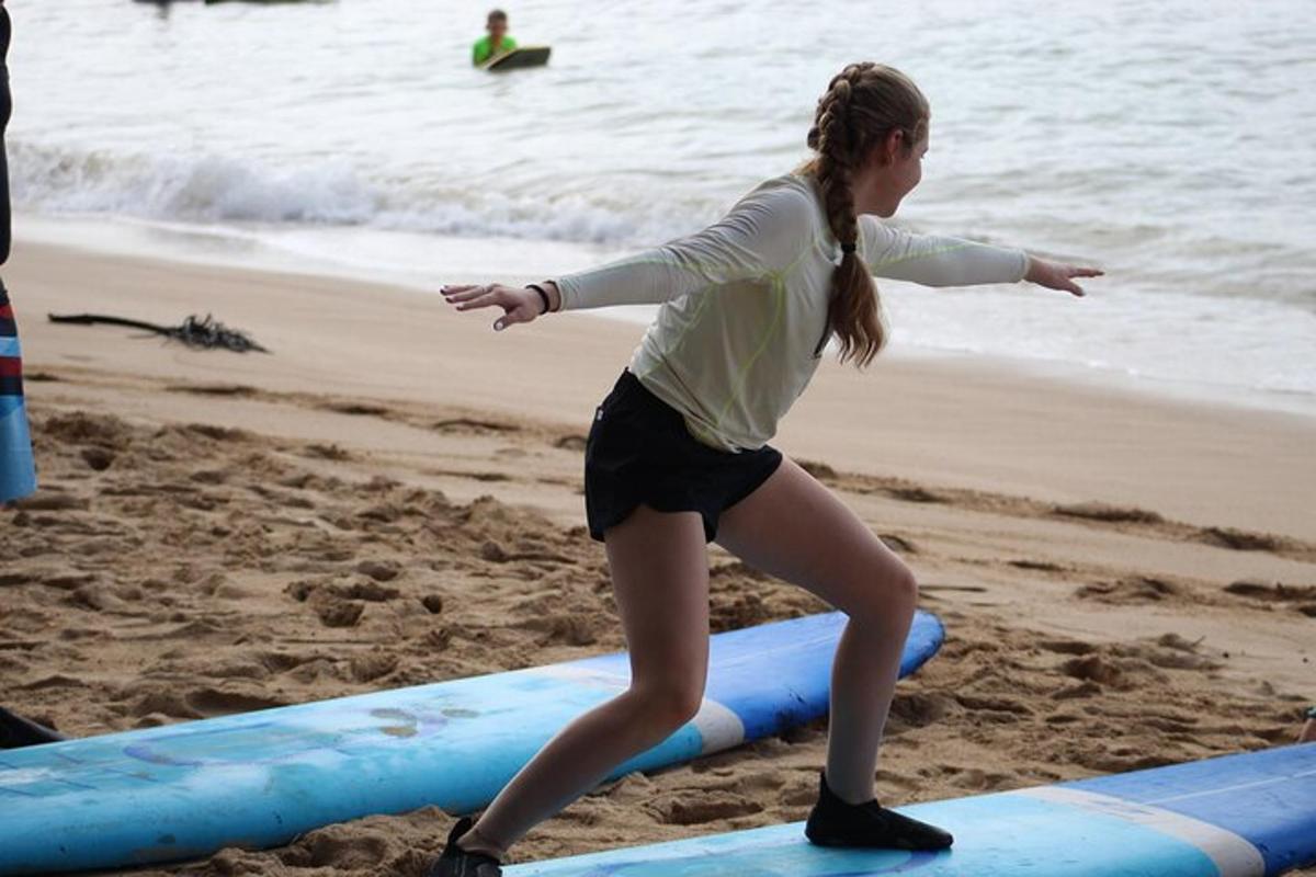 isang batang babae na nakatayo sa isang surfboard sa beach