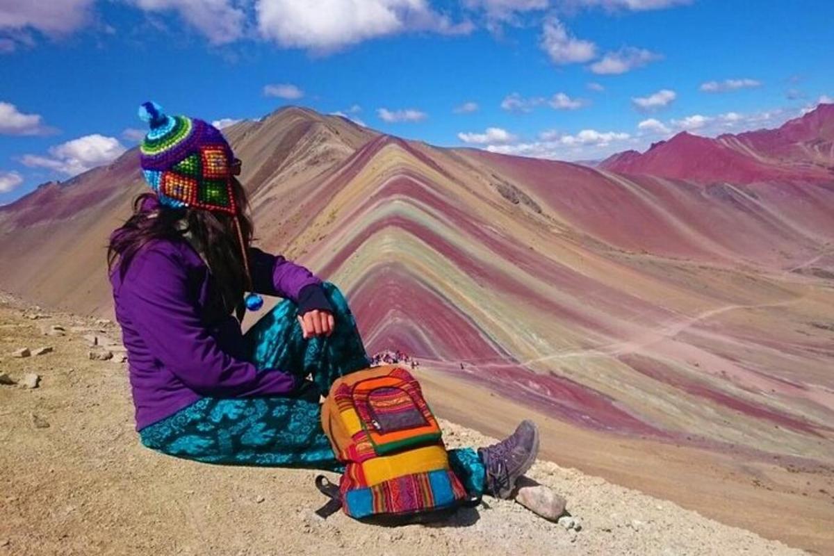 seorang wanita duduk di atas gunung dengan beg galas