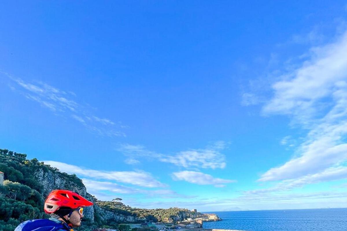 una persona che indossa un casco rosso in piedi su una collina vicino all'oceano